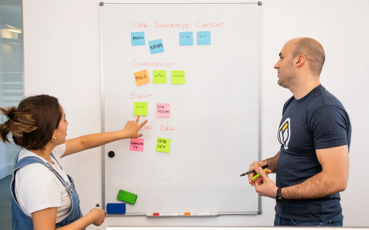 Two colleagues planning a sales pipeline on a whiteboard