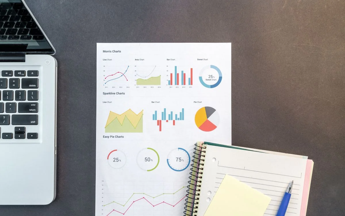 Printed charts and a laptop on an analyst's desk