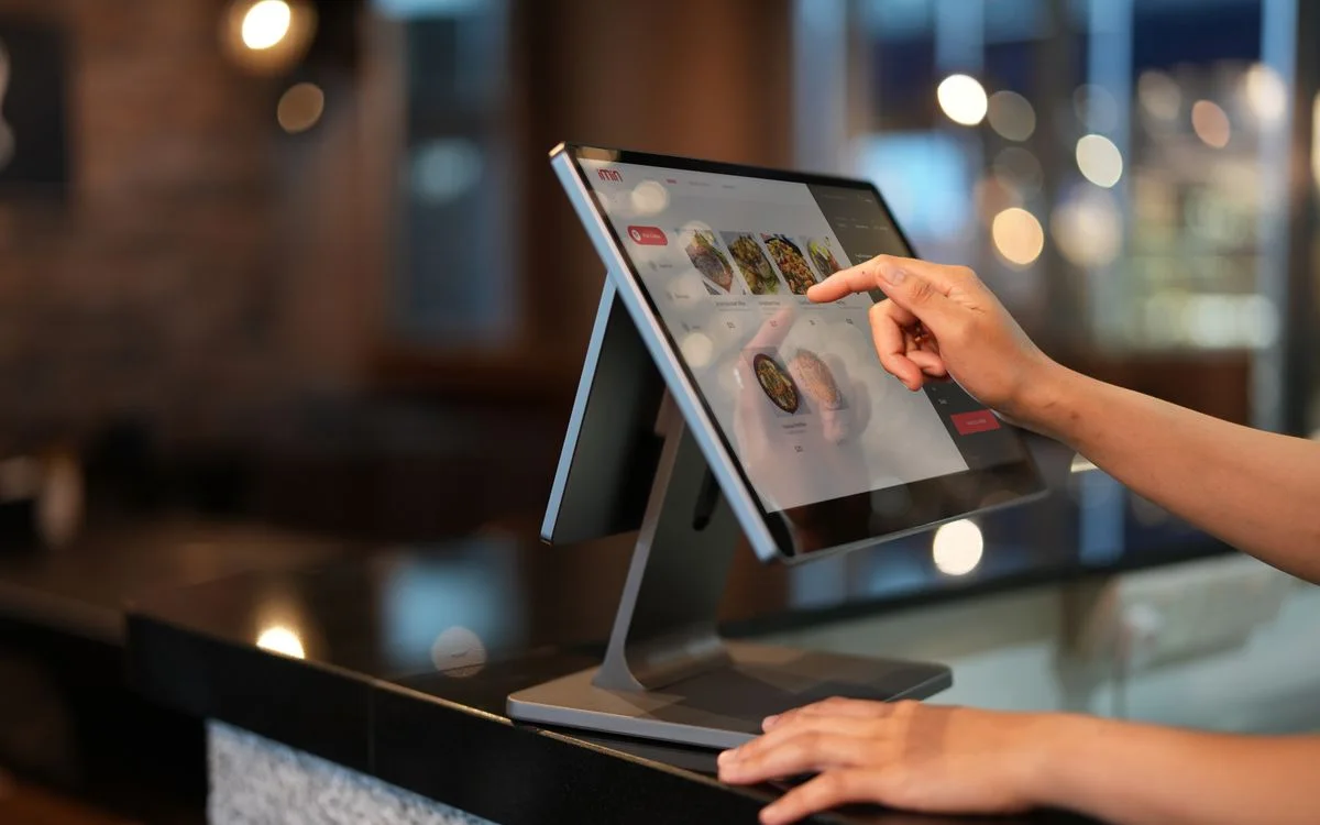 A cashier using a touchscreen point-of-sale terminal